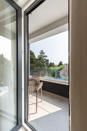 a glass door leading to a balcony with a chair at Villa SHARK 2 with a pool in Novalja
