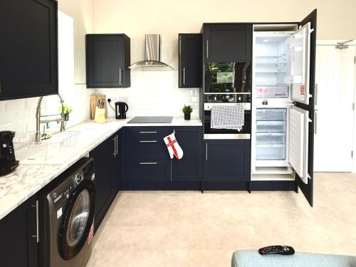 a kitchen with blue cabinets and a washer and dryer at Brand New Lovely Flats by the Forest Tram Stop in Nottingham in Nottingham