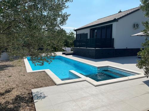 a swimming pool in a yard next to a house at Kuća za odmor Laura in Biograd na Moru
