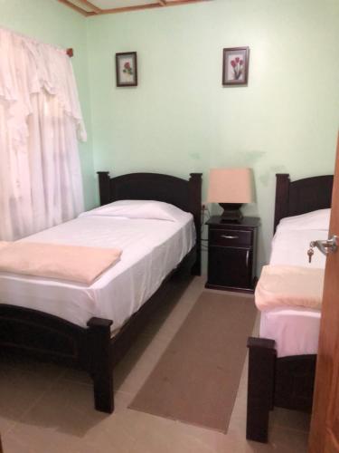 a bedroom with two beds and a lamp and a window at Casita Canto del Bosque Monteverde in Tilarán