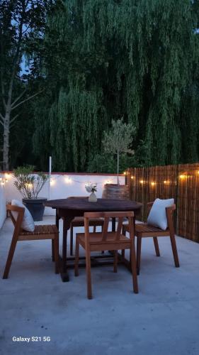 une table en bois et des bancs sur une terrasse éclairée dans l'établissement Chez Gigi, Maisonnette tout confort avec terasse, à Beuvry