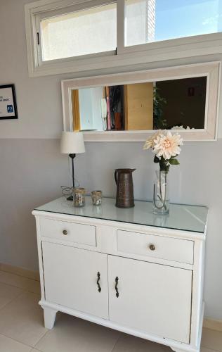 a white dresser with a vase of flowers on it at APARTAMENTOS TURISTICOS LAS CINCO JOYAS in Linares