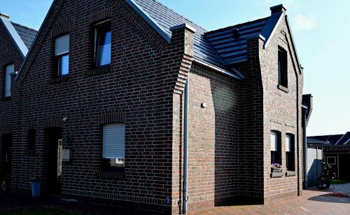 a red brick house with a black roof at fehnhaus-am-see in Papenburg