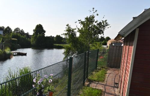 a house with a fence next to a river at fehnhaus-am-see in Papenburg