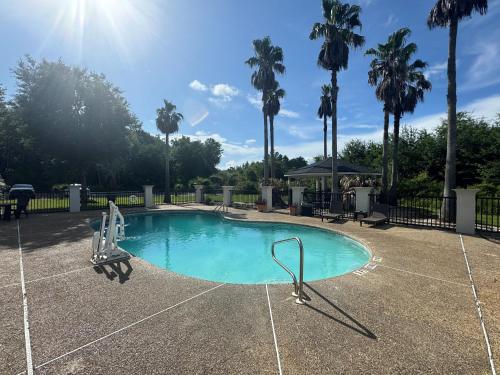 a swimming pool with a slide in a park with palm trees at Wingate by Wyndham Biloxi - Ocean Springs in Biloxi