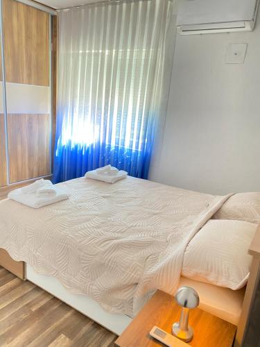 ein Schlafzimmer mit einem großen weißen Bett mit einem blauen Vorhang in der Unterkunft Kuzmanovski Apartments in Bitola