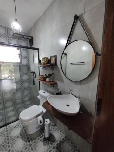 Un baño con lavabo, inodoro y espejo. en Alto Maanaim, en Sapucaí-Mirim