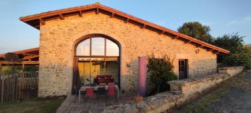une maison en pierre avec une grande fenêtre et des chaises rouges dans l'établissement Gîte Le Bouton d'Or 3 étoiles 8 kms PuyDuFou, à Chambretaud