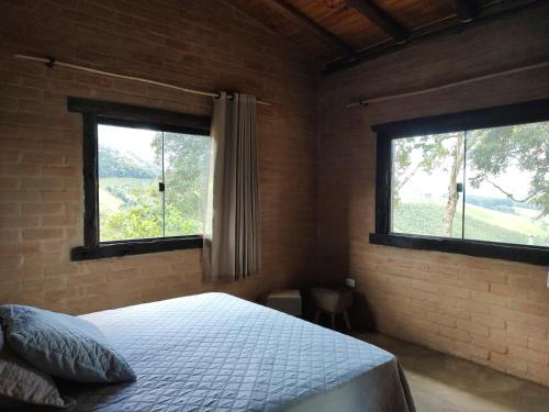 1 dormitorio con 2 ventanas en una pared de ladrillo en Alto Maanaim, en Sapucaí-Mirim