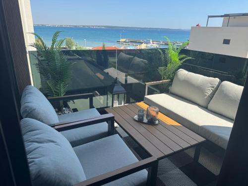 a balcony with a table and couches and the ocean at HORIZON Privlaka3 in Privlaka