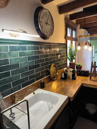 une cuisine avec un évier et une horloge murale dans l'établissement Gîtes à la ferme, Le Jardin Bleu, à Tulette