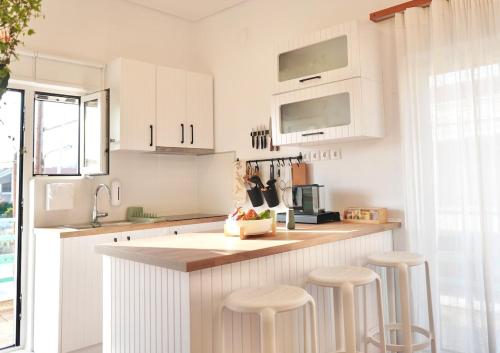 a kitchen with white cabinets and bar stools at Yoma in Amarinthos