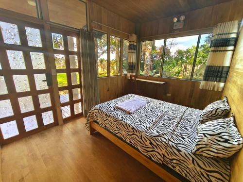 a zebra print bed in a room with windows at Retazos Eco Hotel in Iquitos