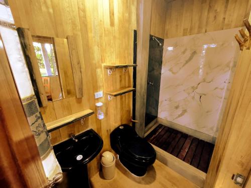 a bathroom with a black toilet and a shower at Retazos Eco Hotel in Iquitos