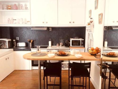 une cuisine avec une table avec des chaises et un micro-ondes dans l'établissement Villa Iena 4 étoiles - Centre Ville Perpignan, à Perpignan