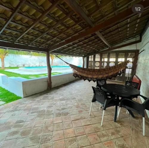 a patio with a table and chairs and a hammock at Casarão da Barra - Barra De Cunhaú in Canguaretama