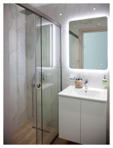 a white bathroom with a sink and a shower at Ammoshine Suite 1 in Nea Peramos