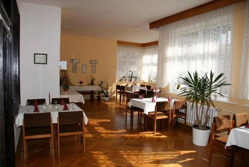 a dining room with white tables and chairs and a room with tables and chairsktop at Hotel Appartementanlage Hermannshöhle in Elbingerode