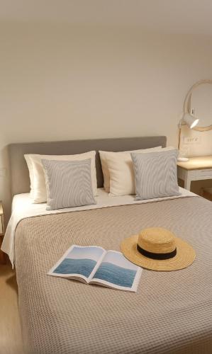 un sombrero de paja y un libro en una cama en Thalassa loft in Tolo, en Tolo