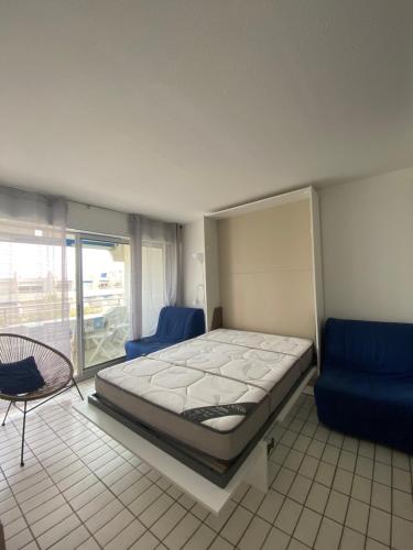 une chambre avec un lit et une chaise bleue dans l'établissement Appartement à la Grande Motte à 50m de la plage, à La Grande Motte