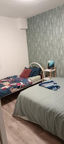 a bedroom with two beds and a chair next to a wall at Ty case péi in Saint-Aignan