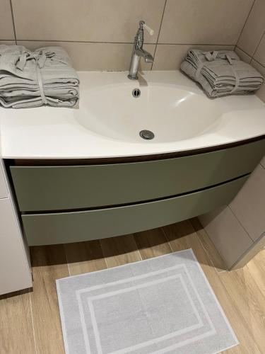 La salle de bains est pourvue d'un lavabo blanc et d'une serviette. dans l'établissement Appartement centre-ville rez-de-chaussée, à La Chapelle-en-Vercors