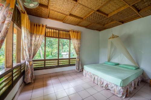 Ecolodge Bukit Lawang في بوكيت لاوانج: غرفة نوم مع سرير في غرفة مع نوافذ