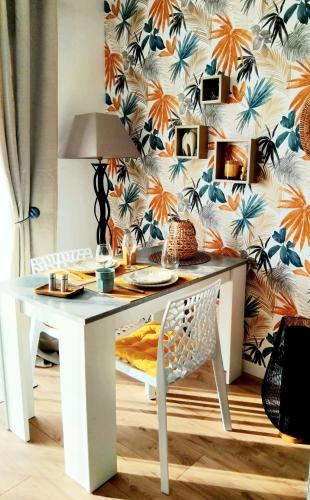 une table et une chaise blanches avec un papier peint dans l'établissement Votre joli studio cosy à Meriadec, à Pluneret