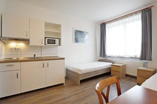 a kitchen with white cabinets and a bed in a room at Penzion Vintrovna in Popůvky