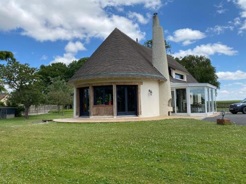 a small house with a roof on a lawn at La maison normande in Rots