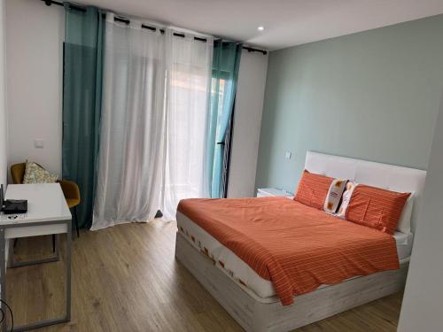 a bedroom with a bed and a desk and a window at Beautiful Modern Townhouse with Parking Included in Machico