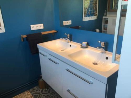 La salle de bains est pourvue d'un lavabo blanc et d'un mur bleu. dans l'établissement Chambre Le Pressoir Saint Christophe, à La Celle-sous-Gouzon