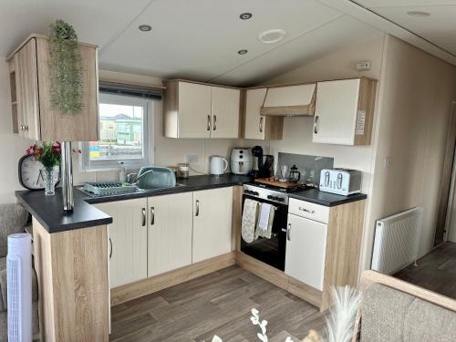 a kitchen with white cabinets and black counter tops at Season Stays in Redcar