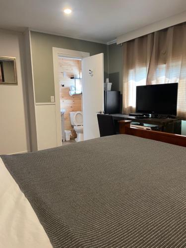 a bedroom with a bed and a television and a bathroom at Greenside Motel in Saint Andrews