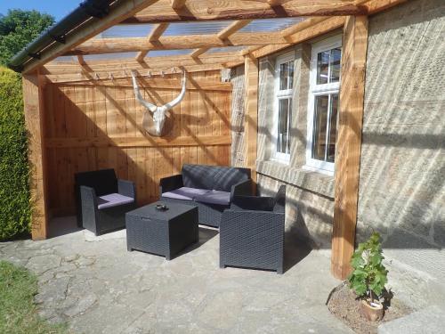 a wooden pergola with two chairs and a couch at Best Tipi in Morayshire with Whisky Barrel Hot Tub in Coltfield