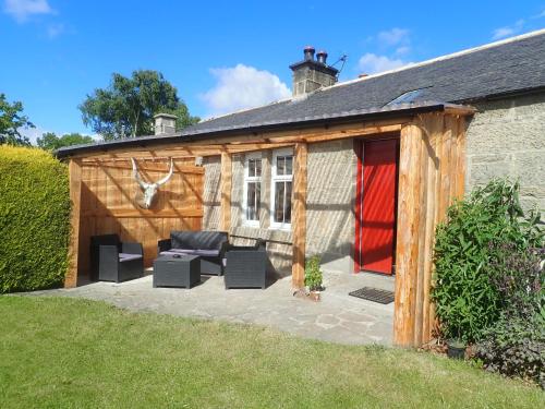 a wooden shed with a couch and chairs in it at Best Tipi in Morayshire with Whisky Barrel Hot Tub in Coltfield