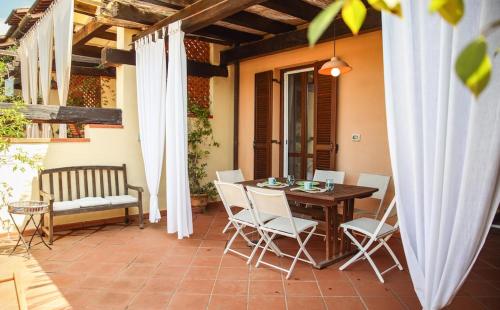 a patio with a wooden table and white chairs at Capalbio Relax - Super terrazza in Capalbio