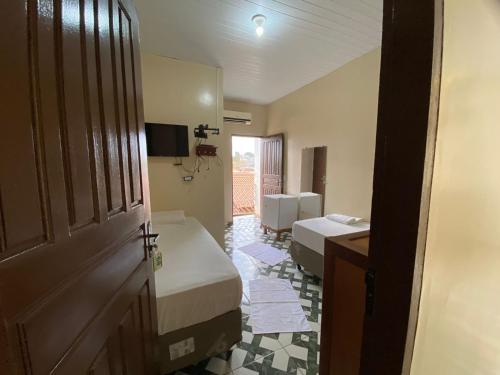 a room with two beds and a television and a door at Junior Hotel in Anapu
