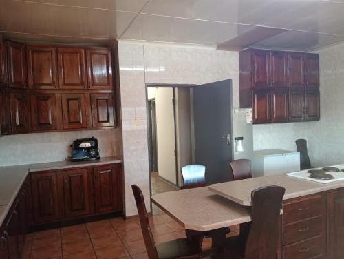 a kitchen with wooden cabinets and a table with chairs at AT Ronnies in Vanderbijlpark