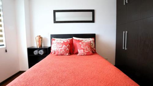 a bedroom with a bed with orange sheets and pink pillows at Park Cimas 3 BR 2 BA Monumental Playas de Tijuana in Tijuana