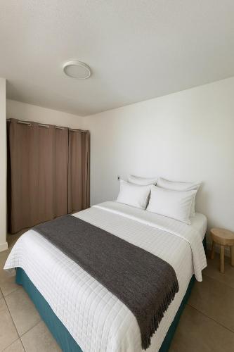 a bedroom with a large bed with white sheets and pillows at Appartement élégant avec vue et climatisation in Fort-de-France