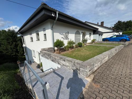 a white house with a stone wall next to a driveway at 160 qm Apartment mit Garten und Stellplatz in Riegelsberg