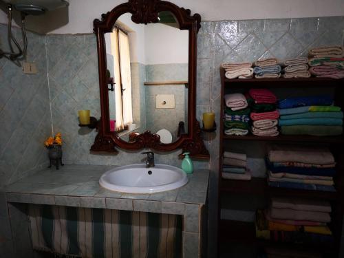 a bathroom with a sink and a mirror and towels at Pinnettu sardo casa di campagna in ecosistema insetti e animaletti simpatici in condivisione,Leggere attentamente Prima di prenotare in Oliena