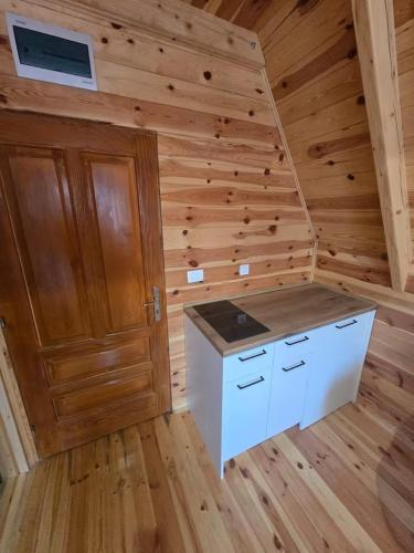 a kitchen in a log cabin with a wooden wall at Old Story Chalets in Žabljak
