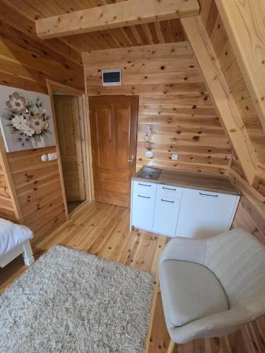 a living room with a white couch and wooden walls at Old Story Chalets in Žabljak