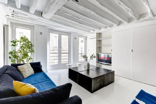 un salon avec un canapé bleu et une télévision dans l'établissement Appartement Rue Montorgueil Calme et Design, à Paris
