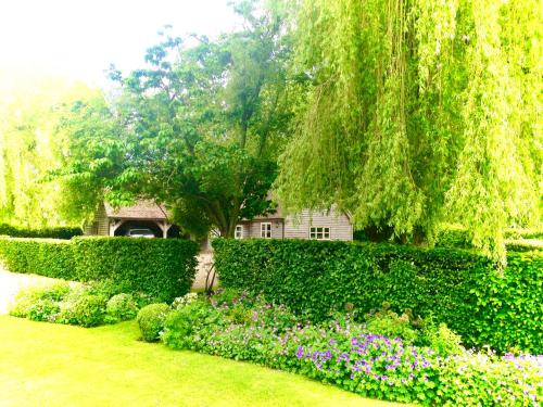 a garden with a tree and flowers in front of a house at Luxurious Country Barn in Baughurst