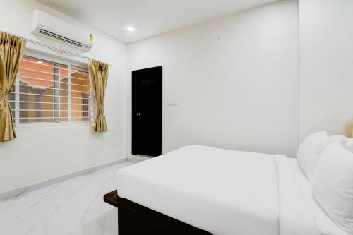 a white bedroom with a bed and a window at Palette Chanda Nagar Near GSM Mall in Hyderabad