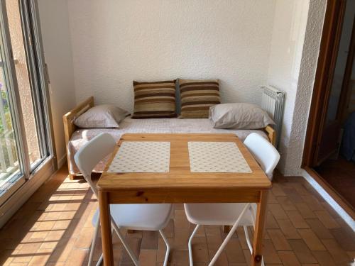 une chambre avec un lit, une table et des chaises dans l'établissement Grand T2 à Gruissan, calme, vue sur le port, à Gruissan