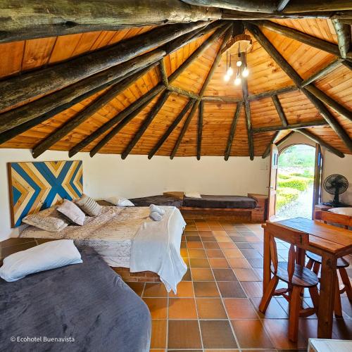 a attic room with two beds and a table at Ecohotel Buenavista in Villa de Leyva